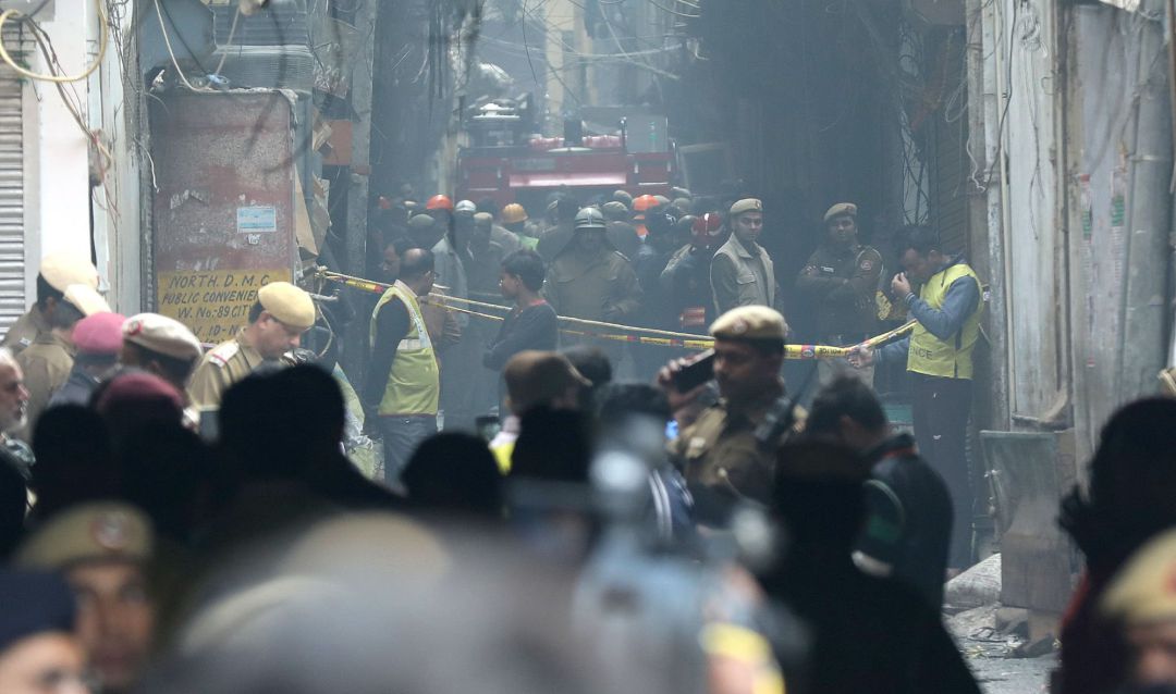 Policías indios, personal de defensa civil y bomberos se paran en un camino estrecho cerca del sitio donde estalló un incendio en Nueva Delhi Policías indios, personal de defensa civil y bomberos se paran en un camino estrecho cerca del sitio donde estalló un incendio en Nueva Delhi