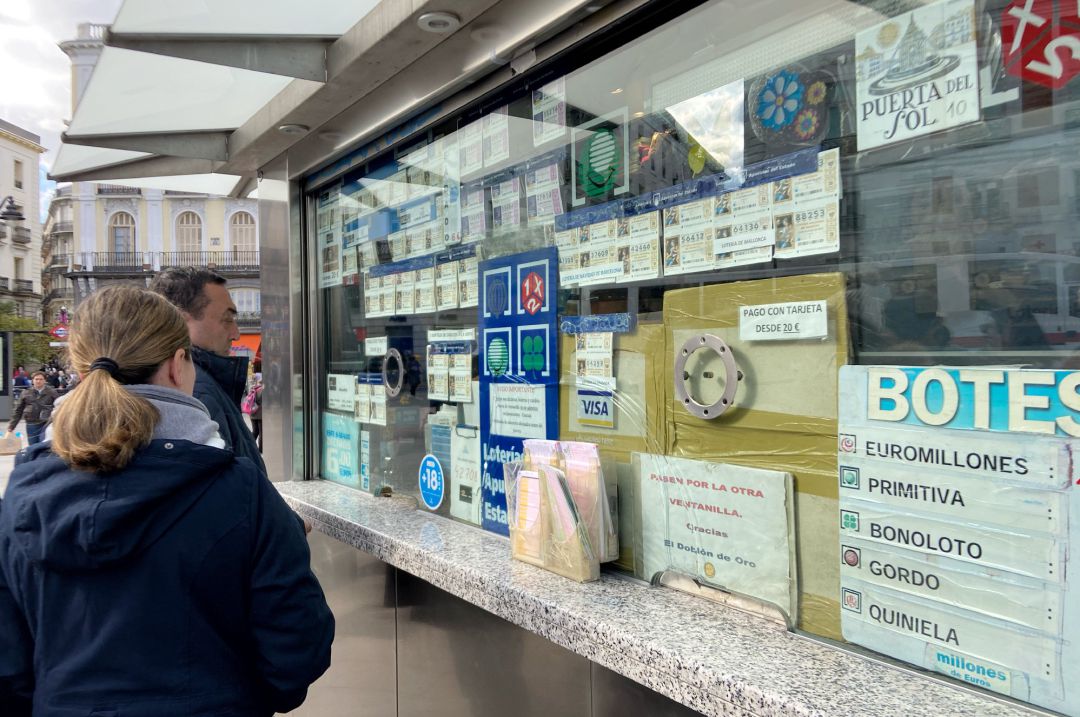 Dos personas compran décimos de Lotería de Navidad en una Administración en la plaza de Puerta del Sol, en Madrid (España). Dos personas compran décimos de Lotería de Navidad en una Administración en la plaza de Puerta del Sol, en Madrid (España).
