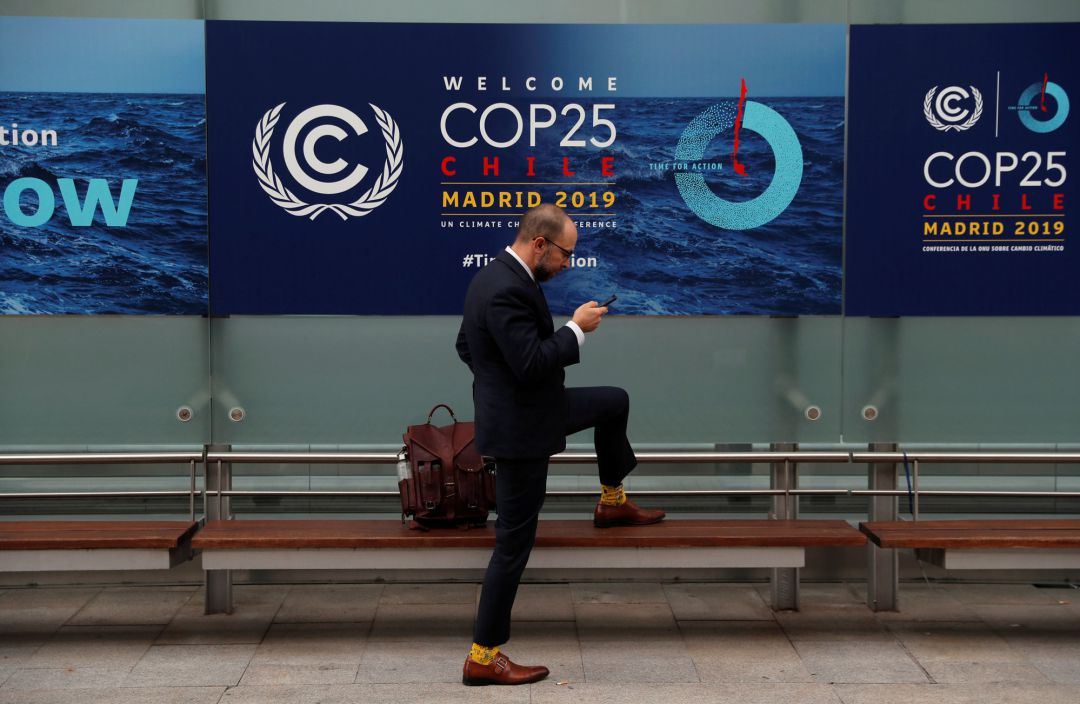 Un hombre mira el móvil delante de un cartel de la COP25 celebrada en Madrid Un hombre mira el móvil delante de un cartel de la COP25 celebrada en Madrid