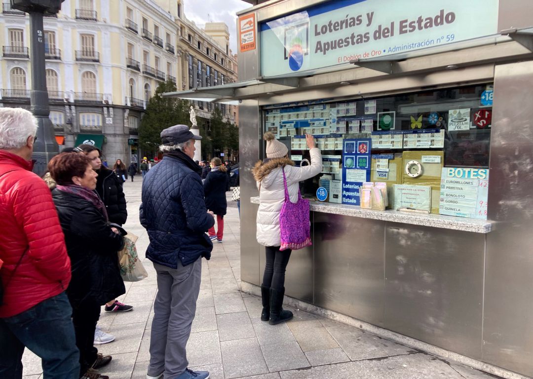 Una mujer compra un décimo de Lotería de Navidad en una Administración en la plaza de Puerta del Sol Una mujer compra un décimo de Lotería de Navidad en una Administración en la plaza de Puerta del Sol