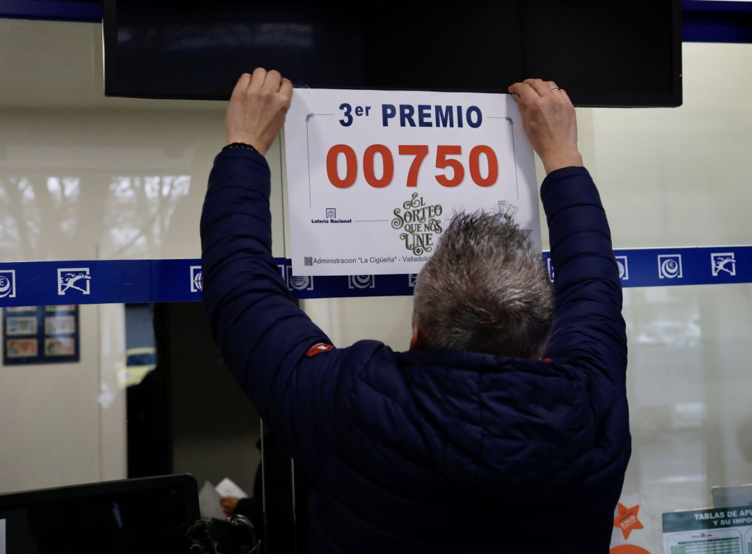 Un hombre cuelga un cartel con el número 00750 Un hombre cuelga un cartel con el número 00750