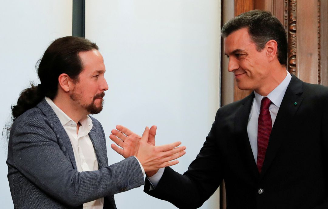 Pedro Sánchez y Pablo Iglesias estrechan manos ante el nuevo Gobierno de coalición. Pedro Sánchez y Pablo Iglesias estrechan manos ante el nuevo Gobierno de coalición.