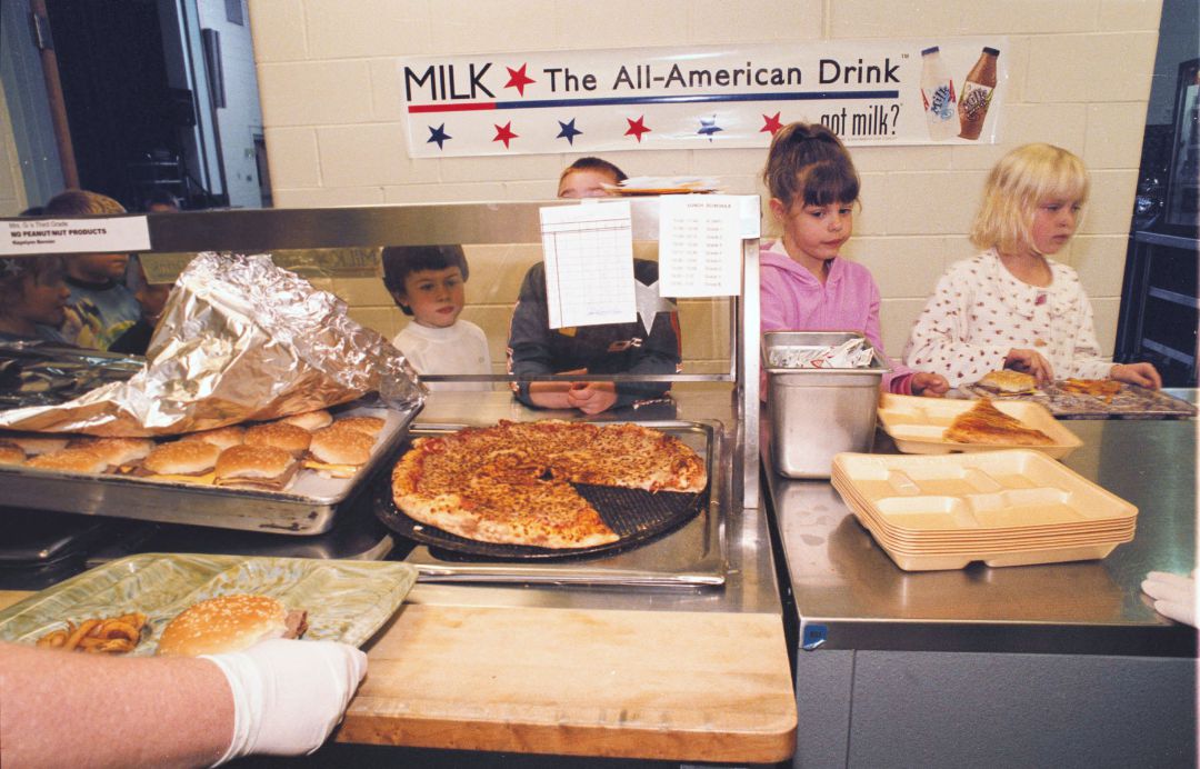 Unos niños esperan para recoger su comida en un comedor escolar de Estados Unidos en 2002. En las vitrinas, pizzas y hamburguesas con patatas. Unos niños esperan para recoger su comida en un comedor escolar de Estados Unidos en 2002. En las vitrinas, pizzas y hamburguesas con patatas.