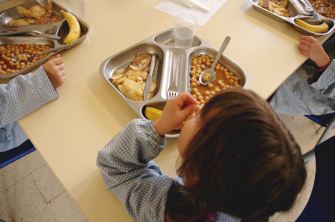 Una niña come en un comedor escolar. Una niña come en un comedor escolar.