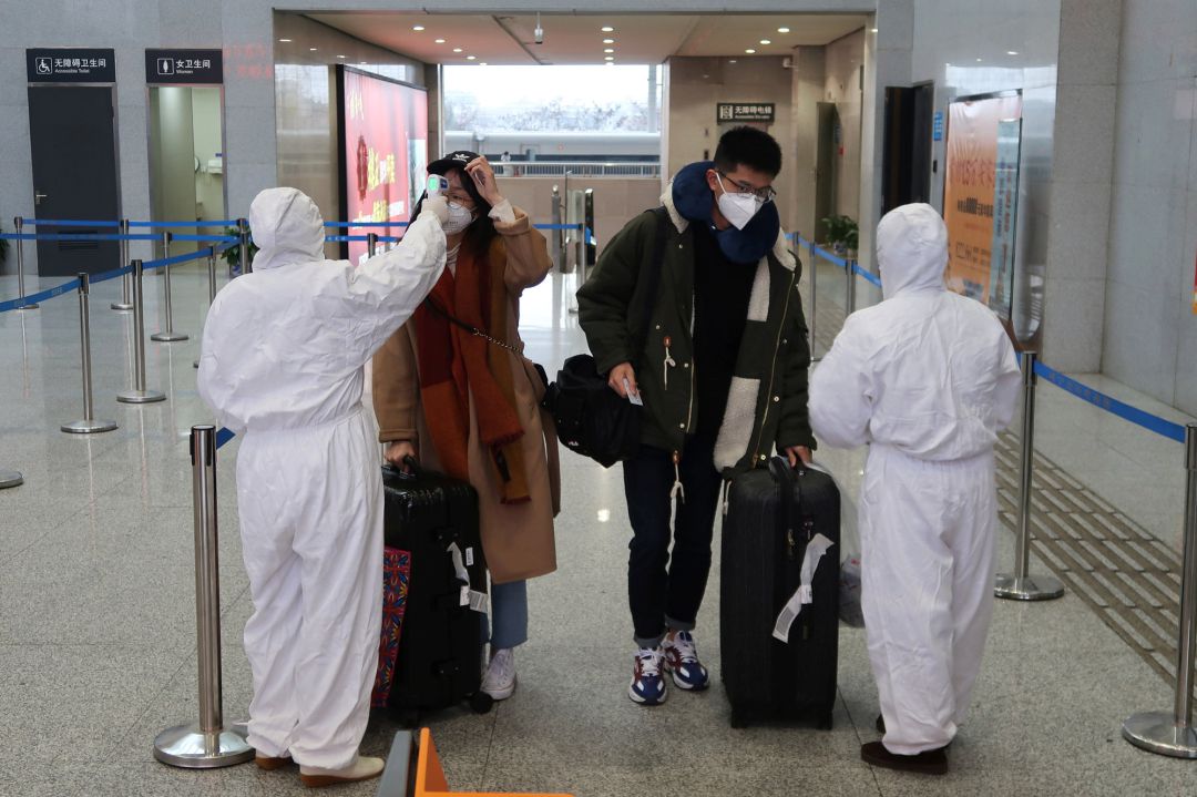 Los trabajadores en trajes de protección controlan la temperatura de los pasajeros que llegan a la estación Xianning North, una ciudad que limita con Wuhan Los trabajadores en trajes de protección controlan la temperatura de los pasajeros que llegan a la estación Xianning North, una ciudad que limita con Wuhan