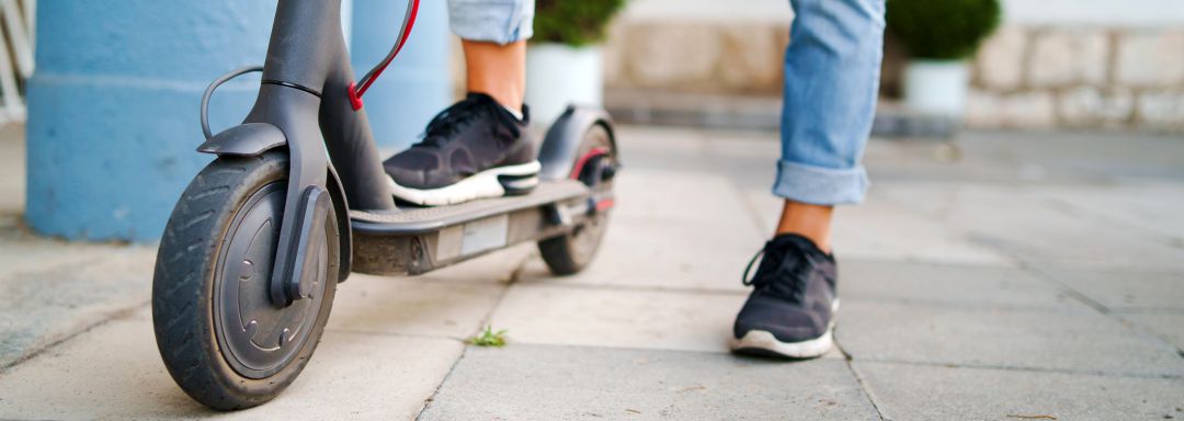 Persona parada en una acera con un patinete eléctrico. Foto de recurso Persona parada en una acera con un patinete eléctrico. Foto de recurso