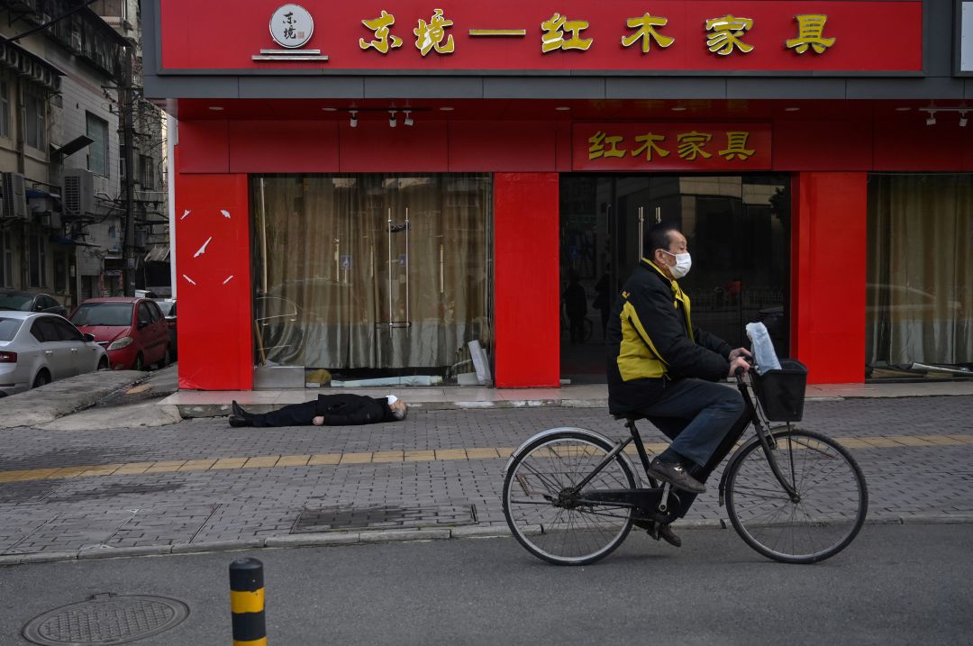 Un hombre yace en la calle muerto mientras otro pasa a su lado en bicicleta Un hombre yace en la calle muerto mientras otro pasa a su lado en bicicleta