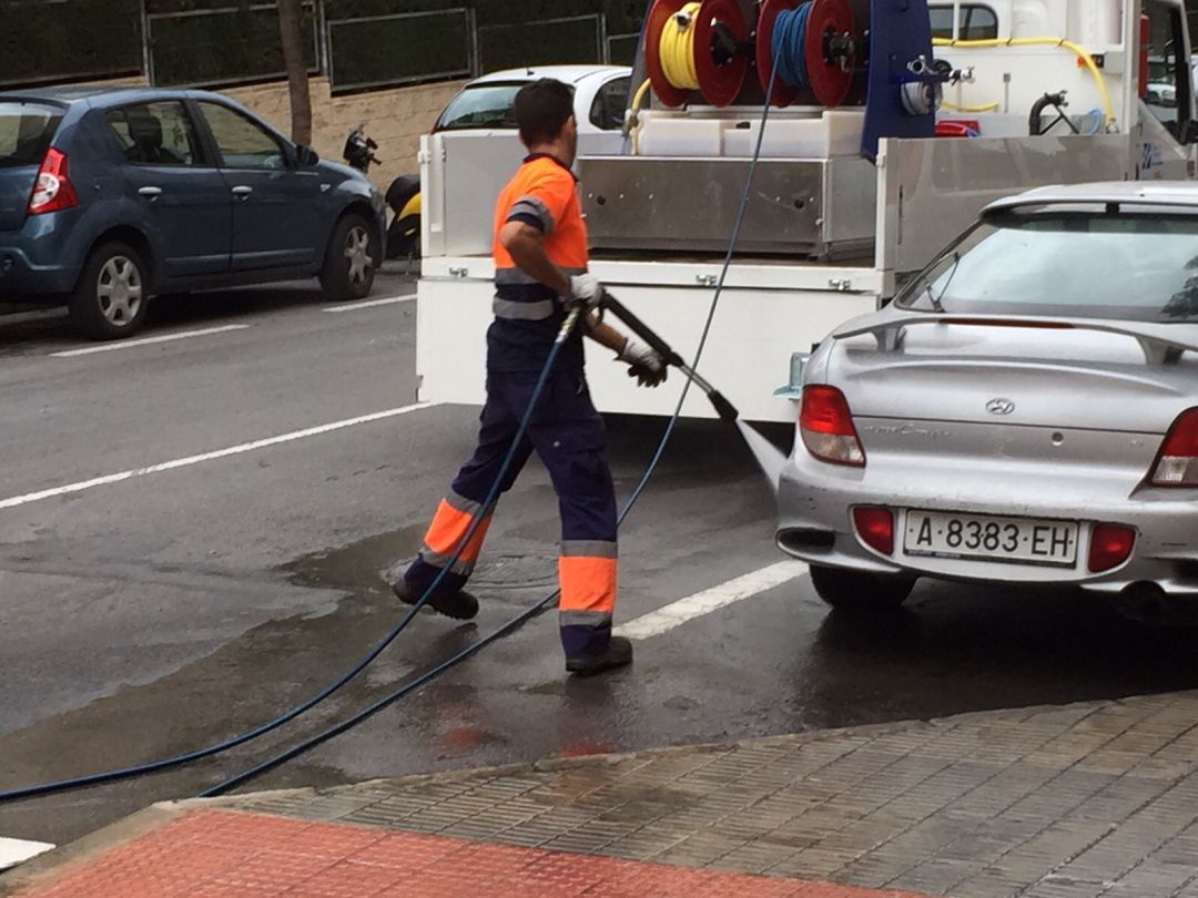 Un trabajador de la contrata de limpieza baldeando una calle de la ciudad Un trabajador de la contrata de limpieza baldeando una calle de la ciudad