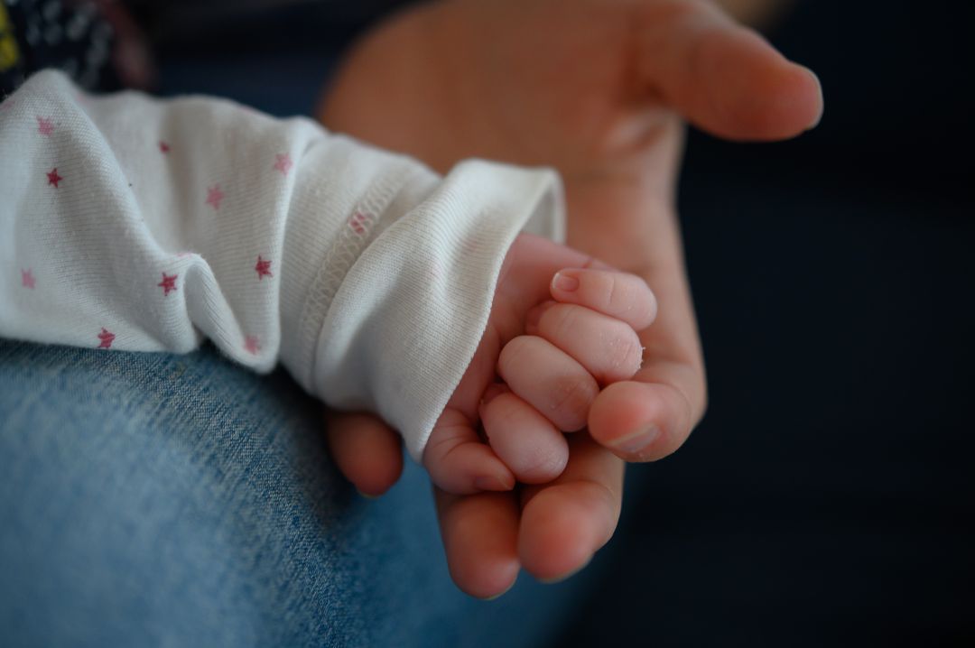 Una mujer sostiene la mano de su hijo de dos semanas de edad. Una mujer sostiene la mano de su hijo de dos semanas de edad.