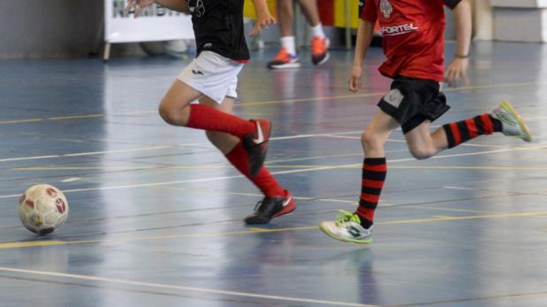 Dos niños juegan al fútbol sala Dos niños juegan al fútbol sala