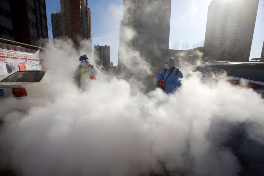 Los trabajadores usan trajes protectores y mascarillas desinfectan un complejo residencial Los trabajadores usan trajes protectores y mascarillas desinfectan un complejo residencial