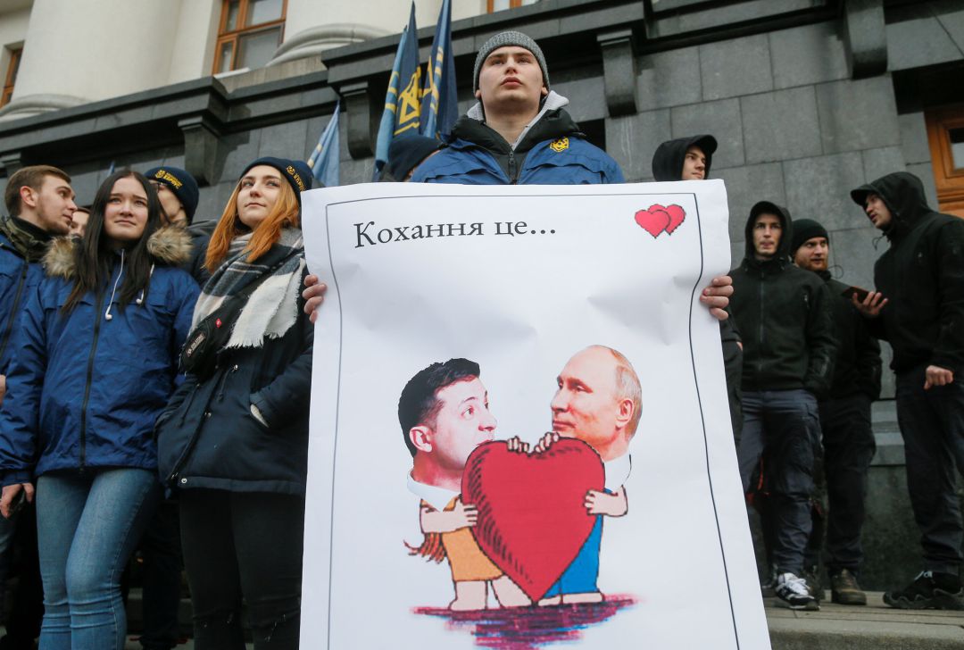 Un manifestante sostiene un póster que representa al presidente ucraniano Volodymyr Zelenskiy y al presidente ruso Vladimir Putin durante una protesta de activistas y simpatizantes de un partido político del Cuerpo Nacional frente al edificio de la Administración Presidencial en el Día de San Valentín en Kiev. El cartel dice: "Amor es..." Un manifestante sostiene un póster que representa al presidente ucraniano Volodymyr Zelenskiy y al presidente ruso Vladimir Putin durante una protesta de activistas y simpatizantes de un partido político del Cuerpo Nacional frente al edificio de la Administración Presidencial en el Día de San Valentín en Kiev. El cartel dice: "Amor es..."