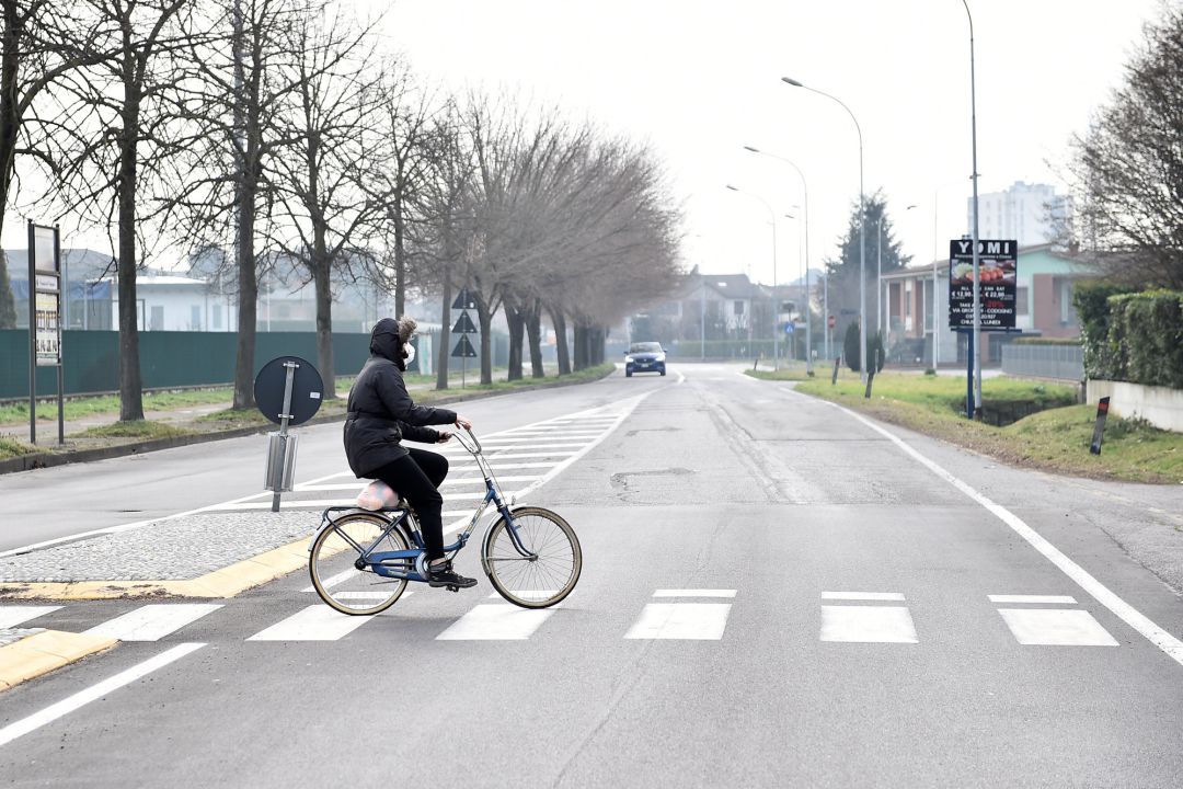 Una persona con mascarilla cruza en bicicleta la ciudad de Codogno, en Italia Una persona con mascarilla cruza en bicicleta la ciudad de Codogno, en Italia
