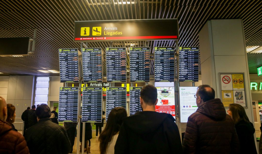 Varios usuarios consultan el panel de llegadas en Barajas. Varios usuarios consultan el panel de llegadas en Barajas.