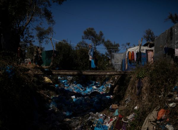 Una niña migrante cruza un puente bajo el que se concentran kilos de basura en el campo de refugiados de Moria, en la isla griega de Lesbos.