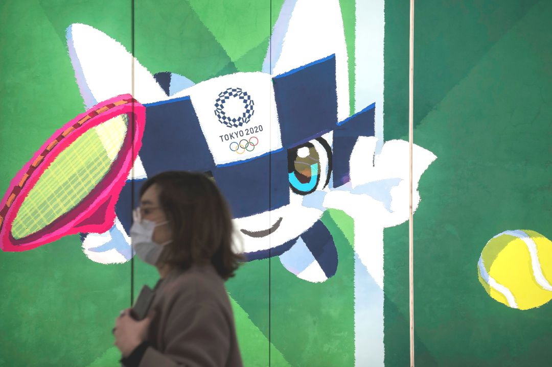 Una mujer pasa por delante de un cartel de los Juegos de Tokio 2020. Una mujer pasa por delante de un cartel de los Juegos de Tokio 2020.