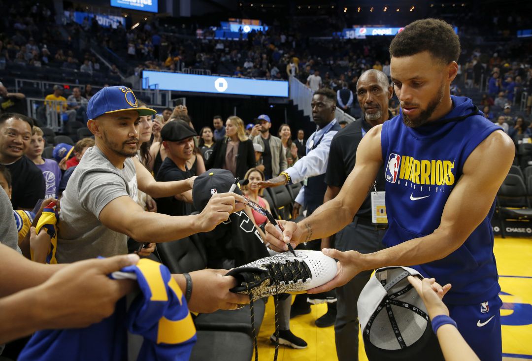 Curry firma una bota a un aficionado. Curry firma una bota a un aficionado.