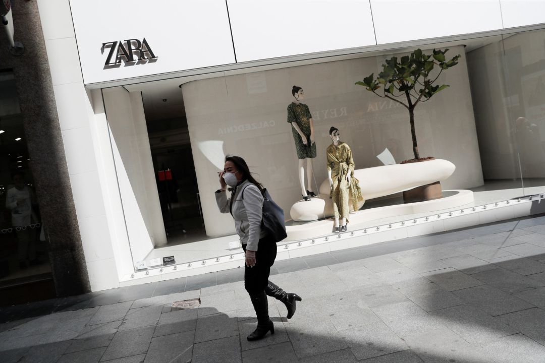 Una mujer pasa por delante de una tienda de Zara con una mascarilla Una mujer pasa por delante de una tienda de Zara con una mascarilla