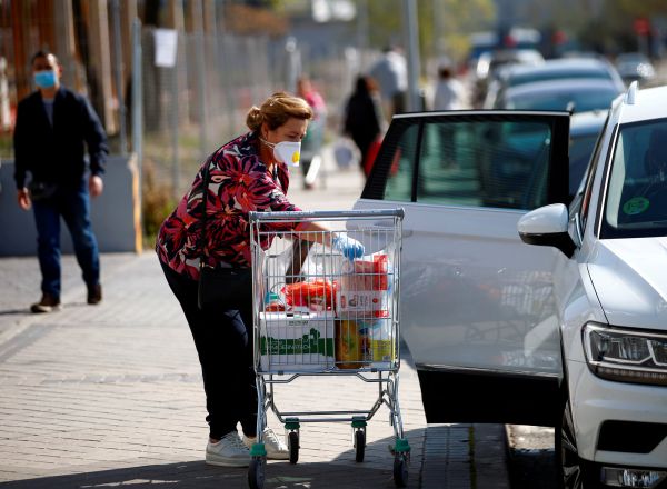 Una mujer con mascarilla mete la compra en un coche en Madrid, en la mañana de este sábado, primer día tras declararse el estado de alarma en España.