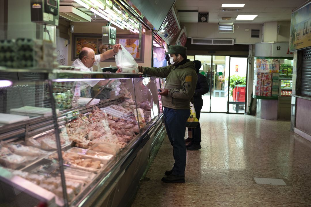 Un vendedor de carne en un mercado da la bolsa con la compra a un cliente, que lleva una mascarilla por la pandemia del coronavirus Un vendedor de carne en un mercado da la bolsa con la compra a un cliente, que lleva una mascarilla por la pandemia del coronavirus
