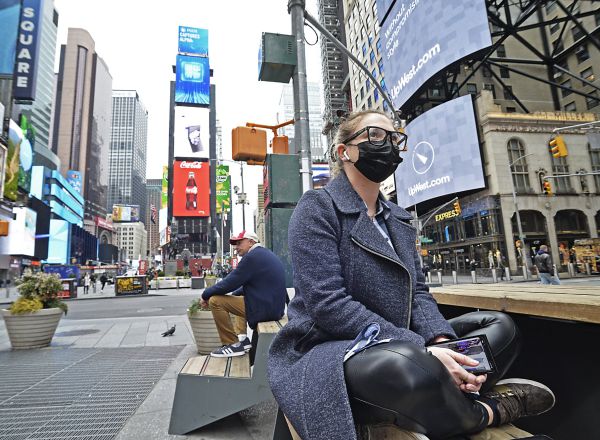 Una mujer sentada en la avenida de Times Square con mascarilla, de las pocas personas que caminan por la ciudad que se sitúa ya como epicentro mundial del virus
