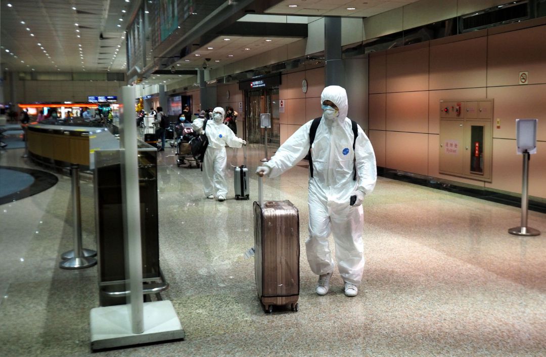 Un hombre y una mujer, vestidos con batas protectoras, llegan al aeropuerto internacional de Taoyuan en Taoyuan, norte de Taiwán. Un hombre y una mujer, vestidos con batas protectoras, llegan al aeropuerto internacional de Taoyuan en Taoyuan, norte de Taiwán.