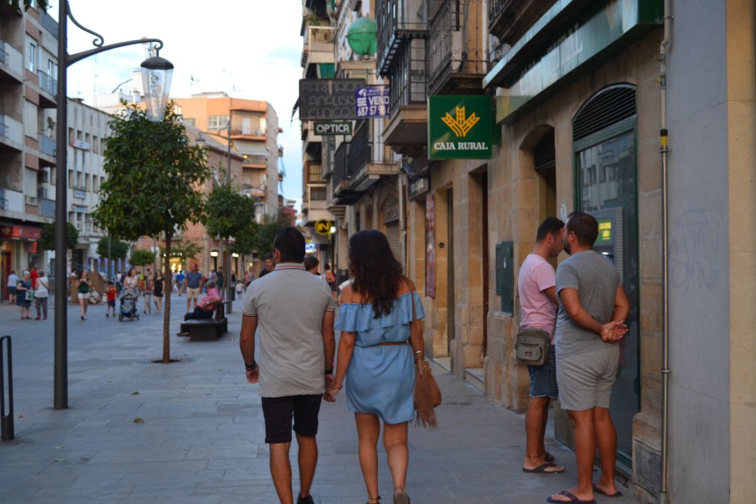 Personas sacando dinero de un cajero a las puertas de una entidad bancaria Personas sacando dinero de un cajero a las puertas de una entidad bancaria