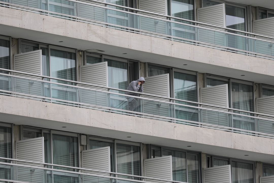 Un hombre asomado al balcón de un hotel Un hombre asomado al balcón de un hotel