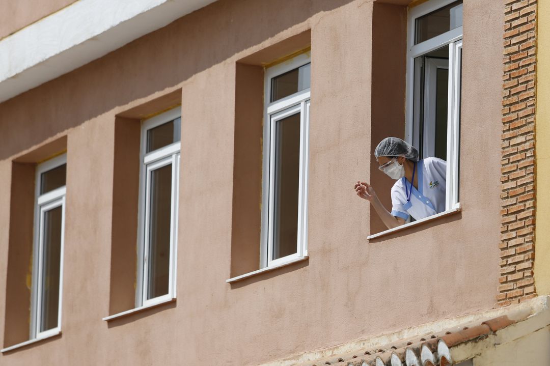 Una trabajadora se asoma a una ventana de el centro de mayores
Una trabajadora se asoma a una ventana de el centro de mayores
