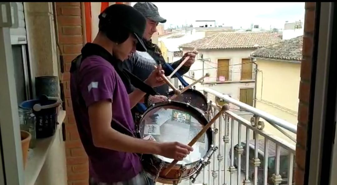 Dos tamboristas en su balcón haciendo sonar el tambor Dos tamboristas en su balcón haciendo sonar el tambor