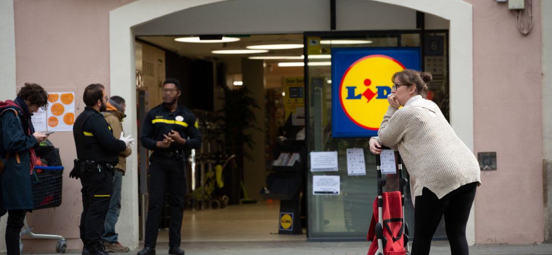 Una mujer espera con su carro de la compra a poder entrar a un supermercado Lidl Una mujer espera con su carro de la compra a poder entrar a un supermercado Lidl