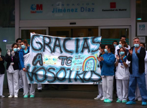 Medical staff from Fundacion Jimenez Diaz hospital hold a banner reading "Thank you all" as neighbours applaud from their balconies in support for healthcare workers, amid the coronavirus disease (COVID-19) outbreak, in Madrid, Spain, March 30, 2020. REUTERS/Sergio Perez