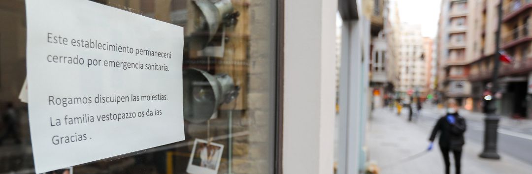 Cartel en la ventana de un establecimiento cerrado en una calle prácticamente vacía Cartel en la ventana de un establecimiento cerrado en una calle prácticamente vacía