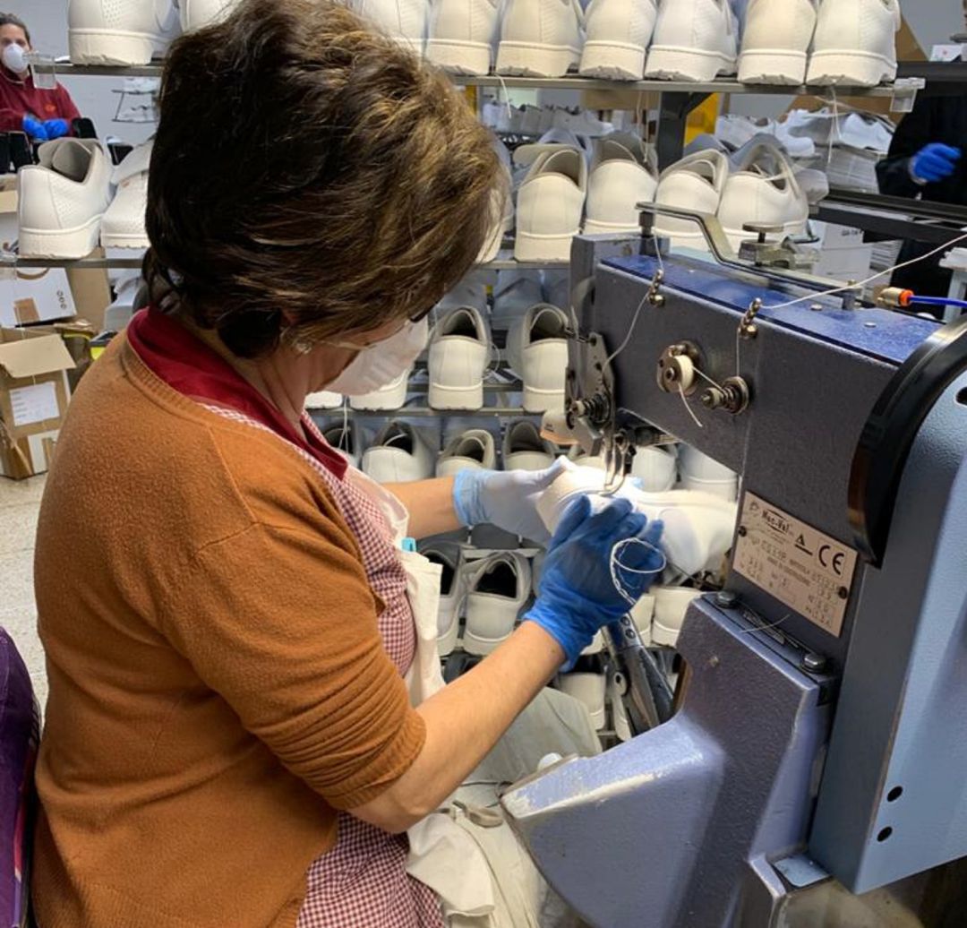 Una trabajadora en su puesto produciendo zapato sanitario Una trabajadora en su puesto produciendo zapato sanitario