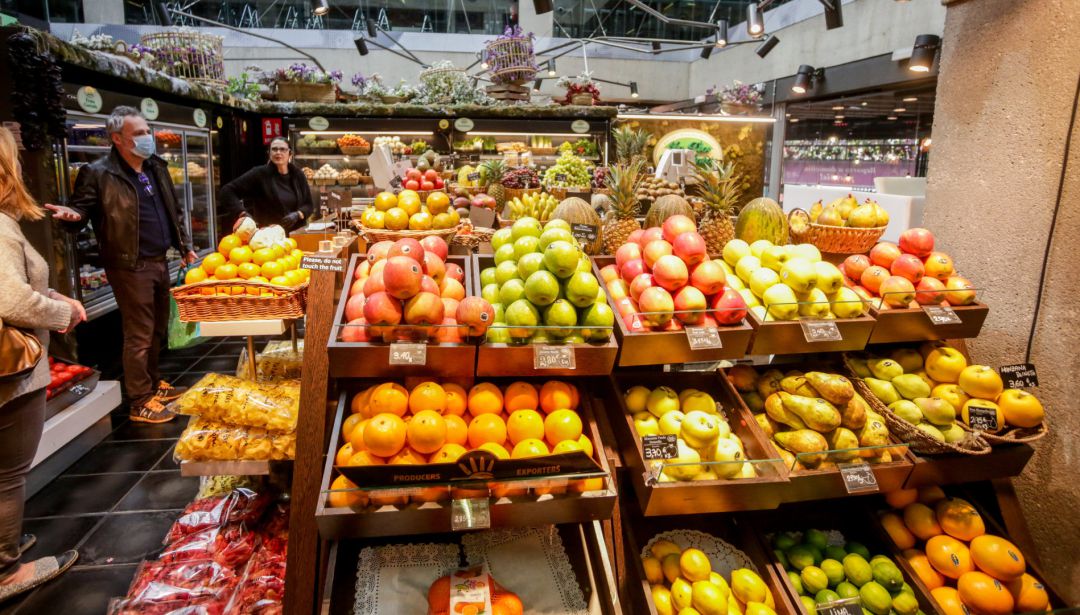 Varios clientes con mascarilla hacen la compra en un puesto de fruta en el mercado de San Antón, que permanece abierto en plena crisis del coronavirus y anuncia que también atiende a domicilio, en Madrid (España). Varios clientes con mascarilla hacen la compra en un puesto de fruta en el mercado de San Antón, que permanece abierto en plena crisis del coronavirus y anuncia que también atiende a domicilio, en Madrid (España).