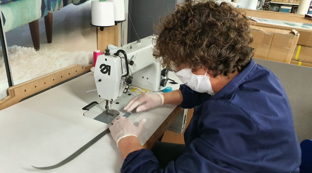 Una trabajadora cosiendo una mascarilla Una trabajadora cosiendo una mascarilla