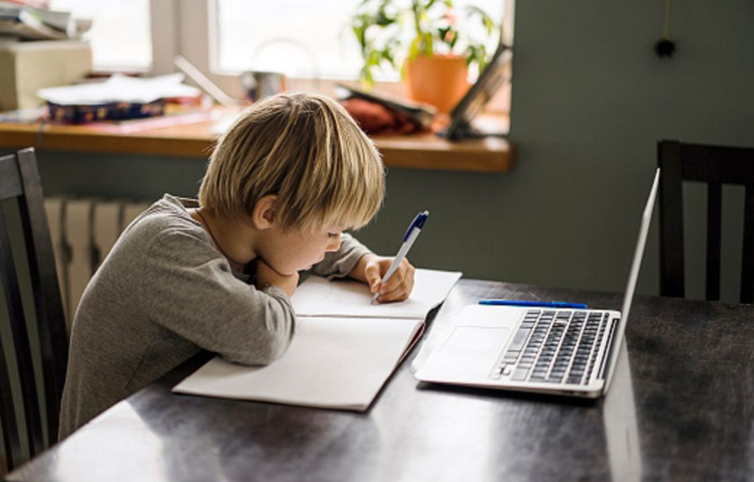 Escolar estudiando en casa con un ordenador Escolar estudiando en casa con un ordenador