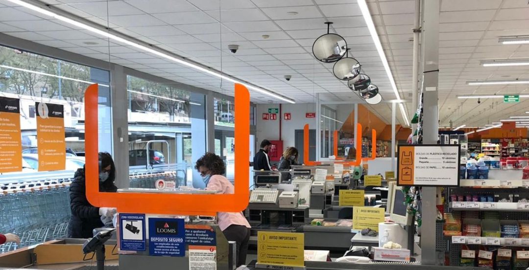 Un supermercado con mamparas en las cajas para mantener la distancia Un supermercado con mamparas en las cajas para mantener la distancia