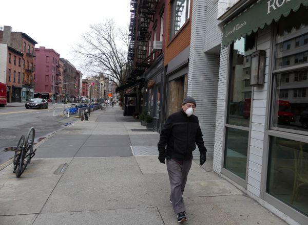 Un hombre con marcarilla camina por una calle vacía de la ciudad de Nueva York.