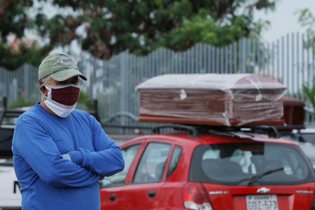 El paciente de una víctima de coronavrus viste una máscara mientras permanece de pie junto a un coche que carga un atáud, en Guayaquil (Ecuador). El paciente de una víctima de coronavrus viste una máscara mientras permanece de pie junto a un coche que carga un atáud, en Guayaquil (Ecuador).
