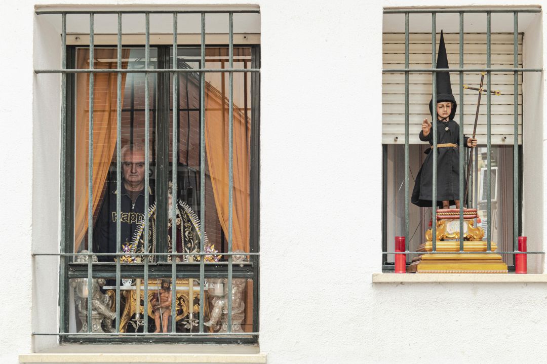 Un hombre se asoma desde la ventana de su casa en Sevilla. en una de las ventanas, una dolorosa, en otra, un niño Jesús vestido de nazareno Un hombre se asoma desde la ventana de su casa en Sevilla. en una de las ventanas, una dolorosa, en otra, un niño Jesús vestido de nazareno