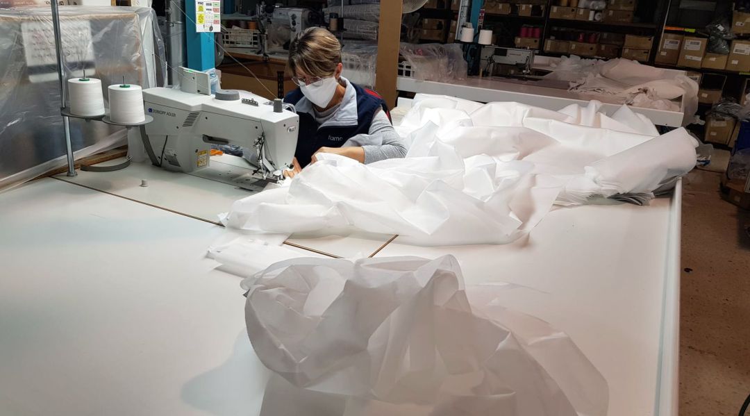 Una de las cosedoras fabricando batas sanitarias Una de las cosedoras fabricando batas sanitarias
