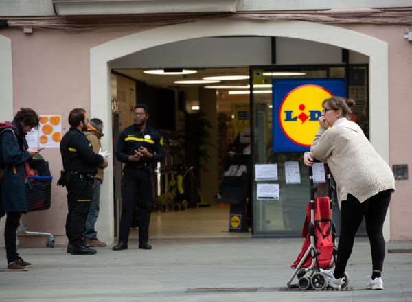 Una mujer espera con su carro de la compra a poder entrar a un supermercado Lidl tras las medidas de aforo impuestas por seguridad, durante el segundo día laborable del estado de alarma por el coronavirus, en Barcelona/Catalunya (España).