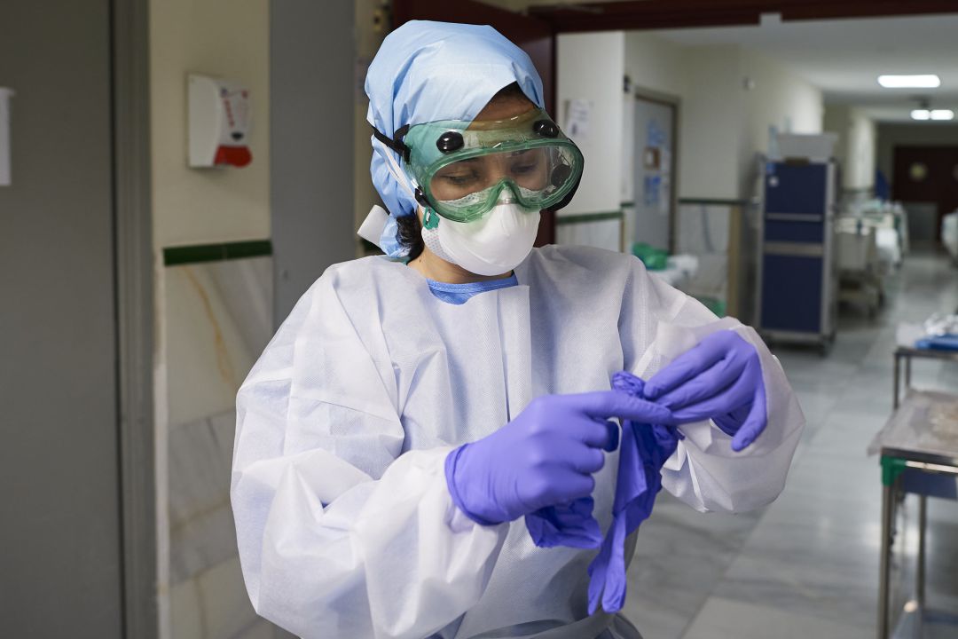 Enfermera preprarándose con su equipo de protección Enfermera preprarándose con su equipo de protección