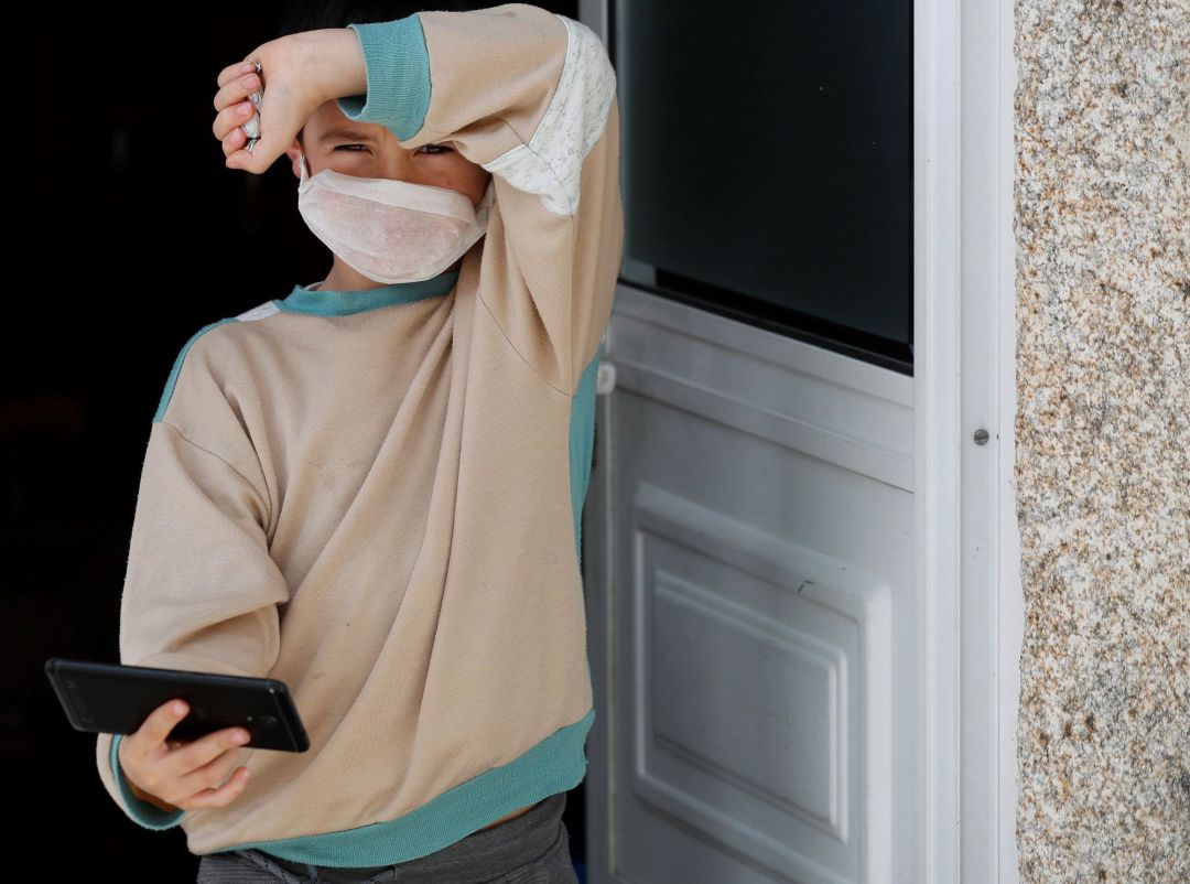 Un niño con una mascarilla casera a las puertas de su casa en Lugo Un niño con una mascarilla casera a las puertas de su casa en Lugo