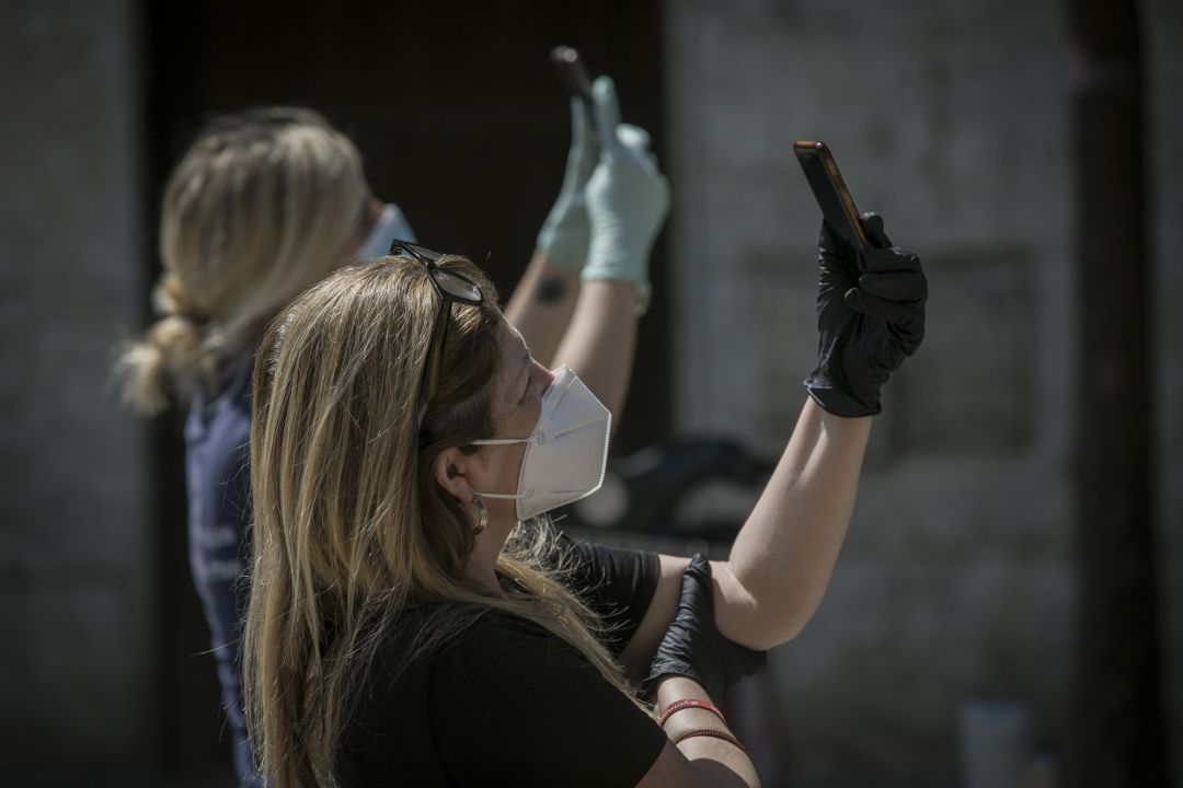 Dos personas protegidas con mascarillas y guantes graban con sus móviles durante el estado de alarma. Dos personas protegidas con mascarillas y guantes graban con sus móviles durante el estado de alarma.