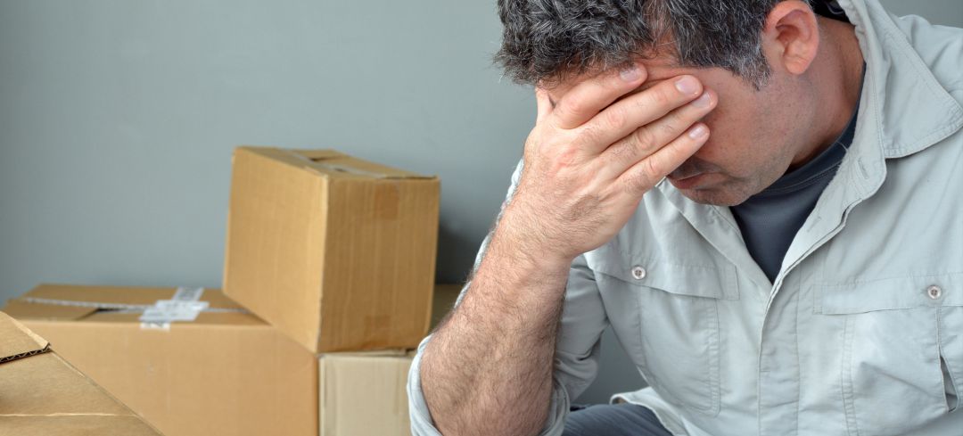 Hombre decaido delante de unas cajas de mudanza Hombre decaido delante de unas cajas de mudanza