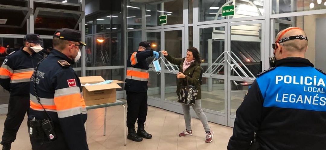 Un miembro de Protección Civil de Leganés entrega una mascarilla a una usuaria del transporte público este lunes por la mañana Un miembro de Protección Civil de Leganés entrega una mascarilla a una usuaria del transporte público este lunes por la mañana