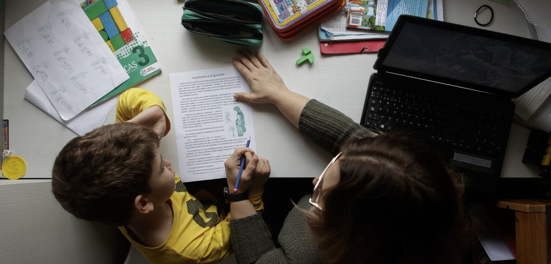 Un niño estudia y hace los deberes en casa con la ayuda de su madre Un niño estudia y hace los deberes en casa con la ayuda de su madre