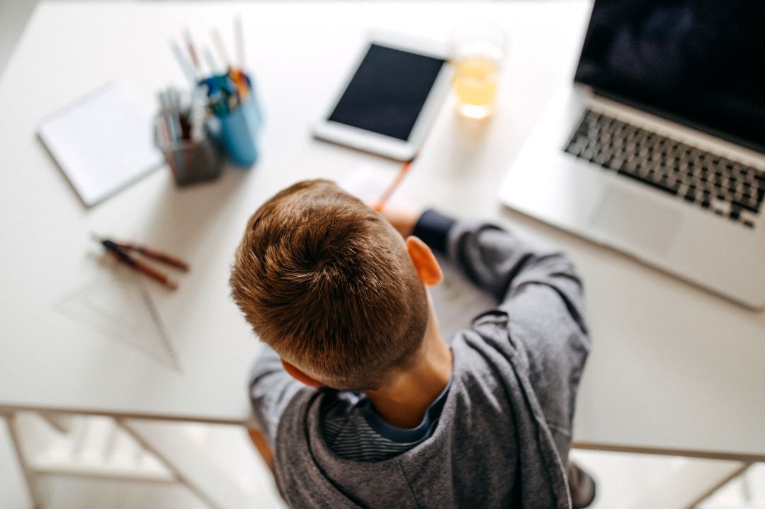 Niño haciendo tareas con el apoyo de la tecnología Niño haciendo tareas con el apoyo de la tecnología